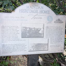 A weathered Heritage Home sign for the McDonald Home among tree branches