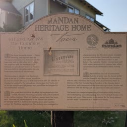 A Heritage Home sign for the Cummins Home with the house behind it