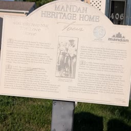A Heritage Home sign for the Love Home with the house behind it
