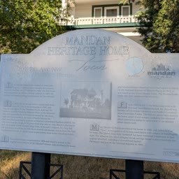 A weathered Heritage Home sign for the Dunlap-Harris Home with Tara behind it