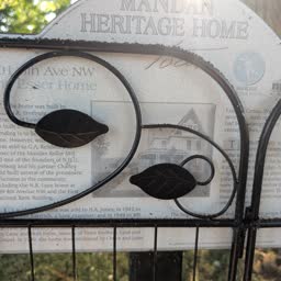 The Freeburg-Esser Home heritage sign heavily obscured by a decorative metal garden screen
