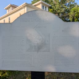 A faded Heritage Home sign for the Stutsman-Wyatt Home with the house behind it